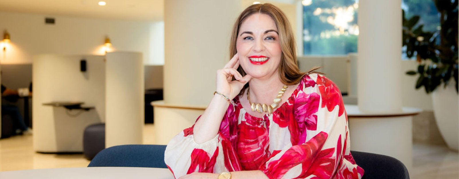 Donna Benjamin Sitting at table smiling with hand under chin